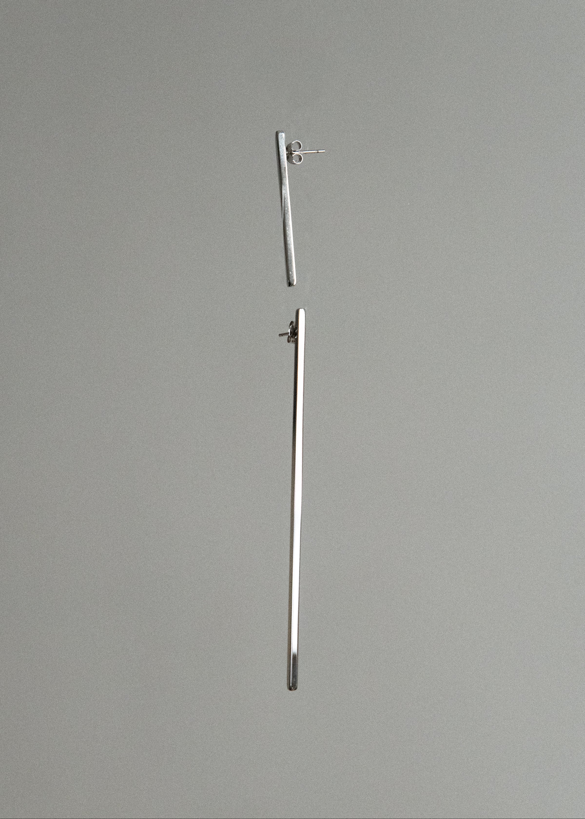 Two silver earrings on a gray background