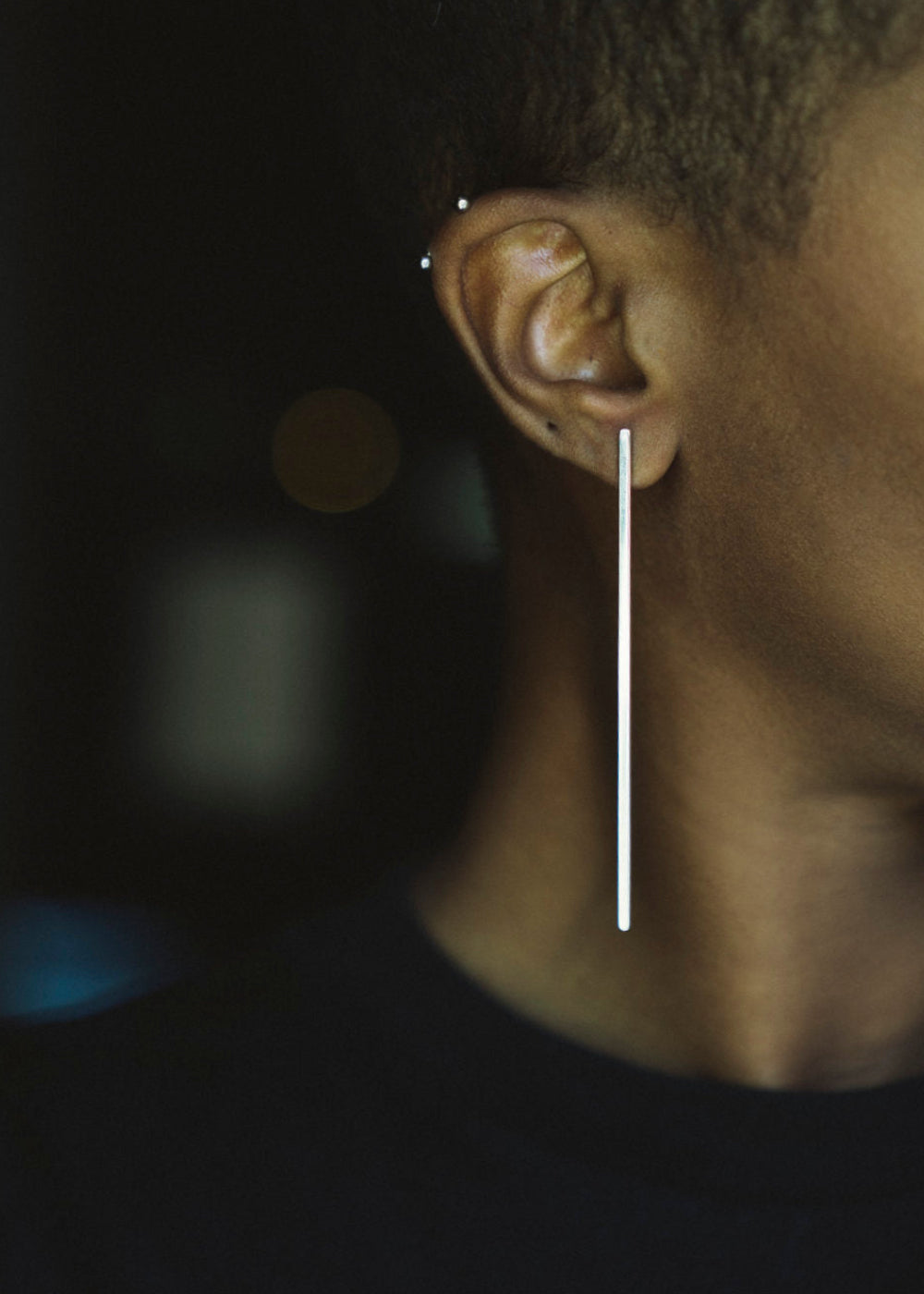 Long silver earring on ear