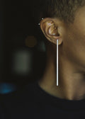 Long silver earring on ear