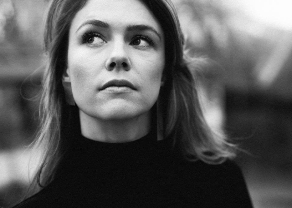 Black and white portrait of a woman with a blurred background and a pair of design silver earrings in two sizes