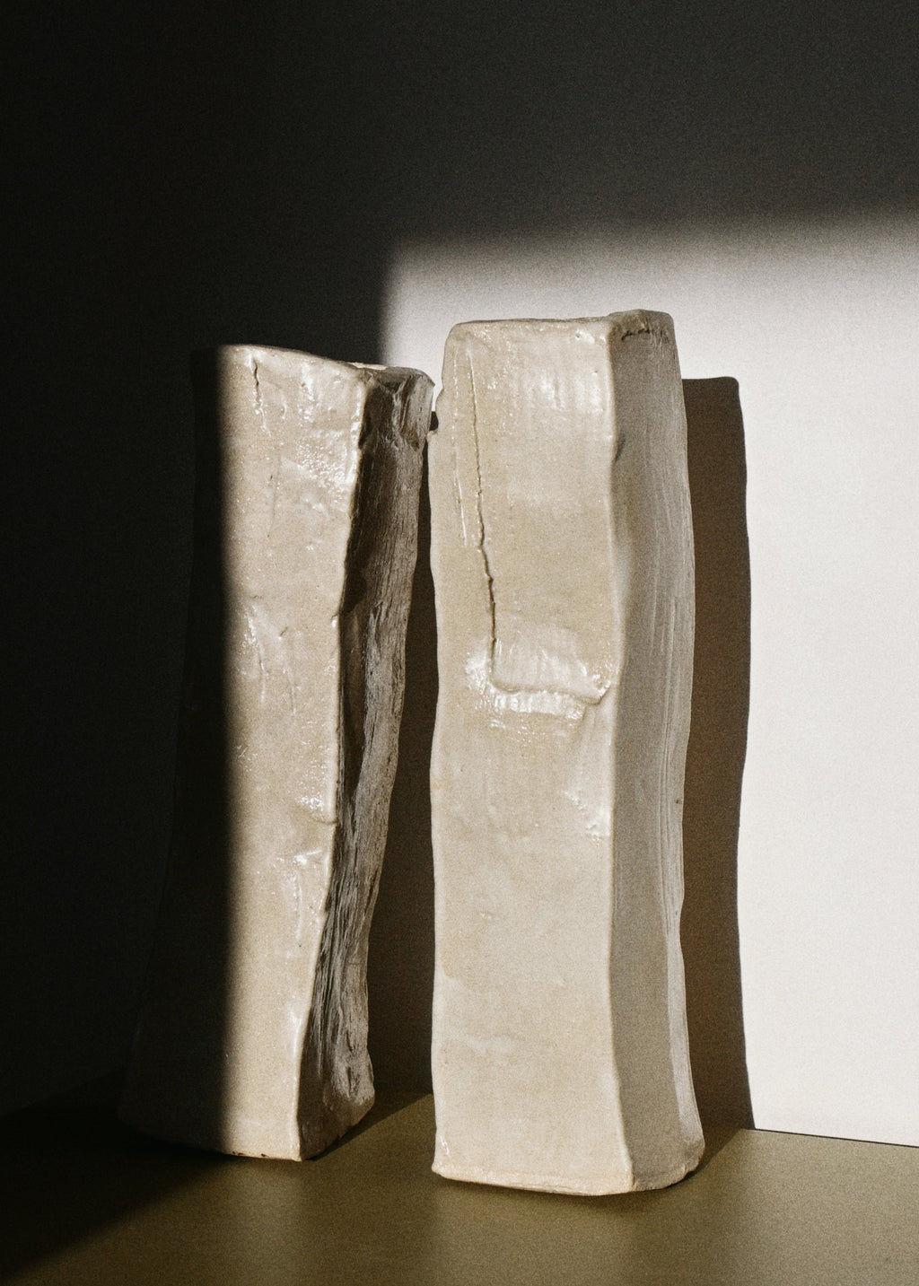 Two sculptural vases on a dark surface with a light background