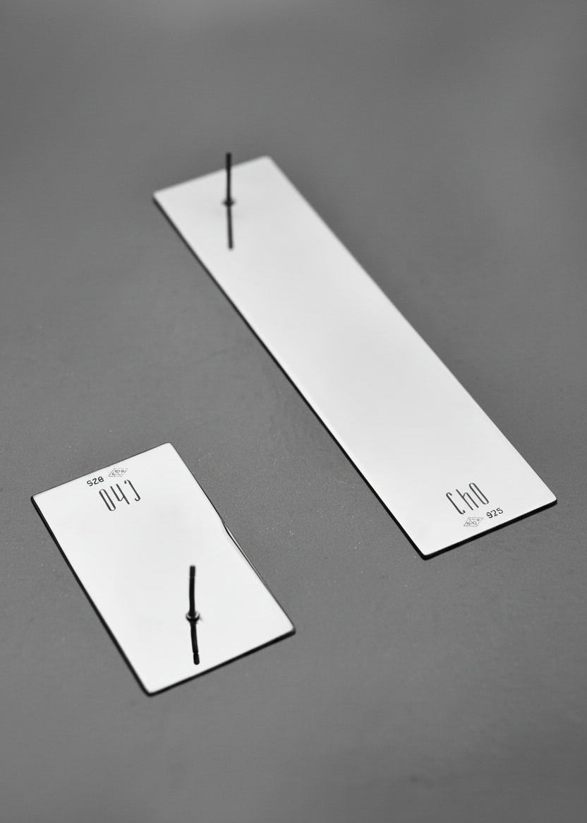 Two rectangular ear studs on a grey background