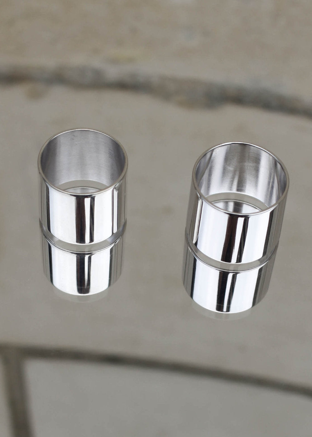 Two silver rings objects on a reflective surface