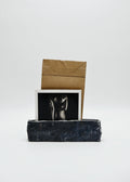 Black handcarved ceramic vessel with a photograph and brown envelope on a white background