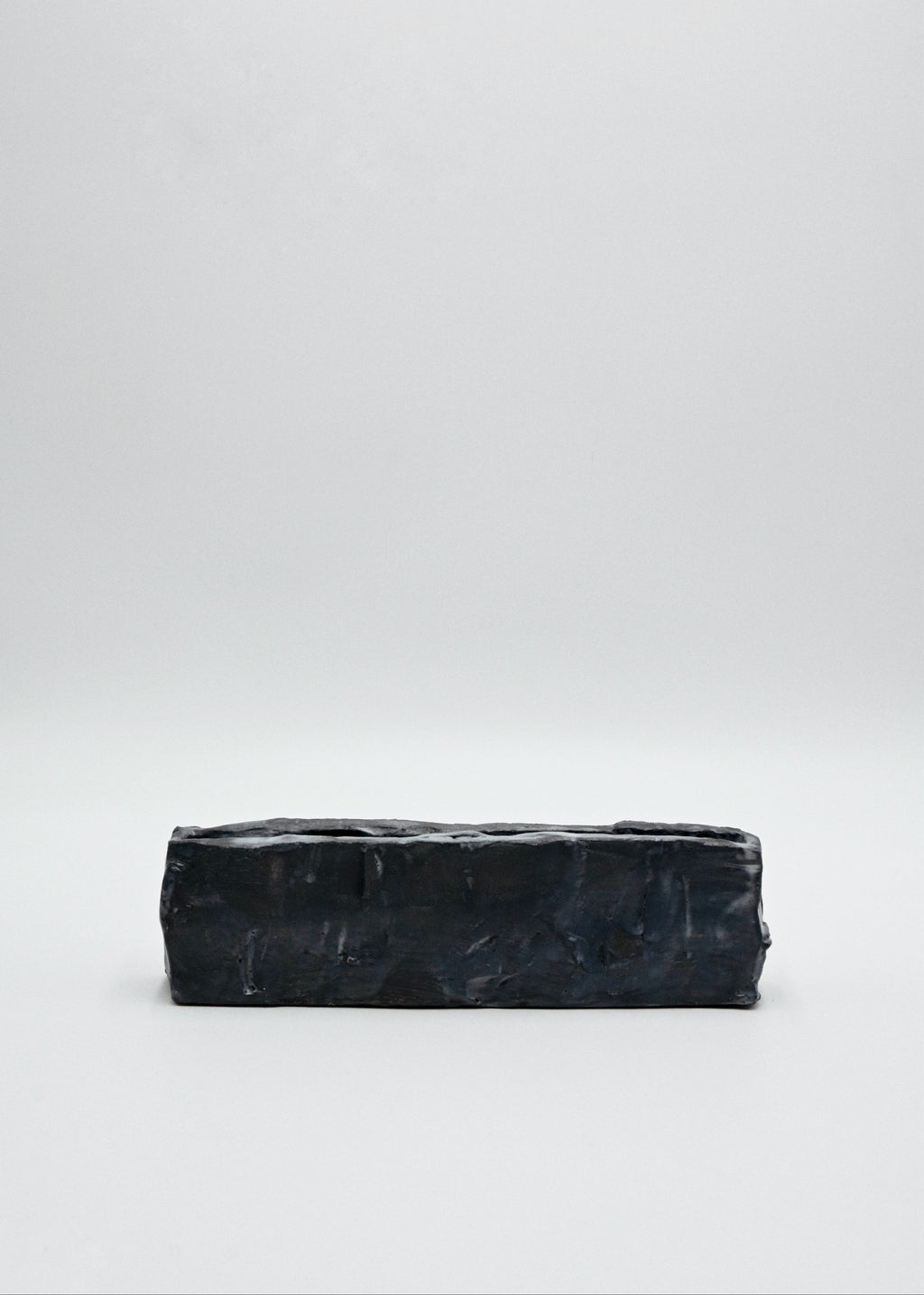 Black rectangular handcarved ceramic vessel on a white background