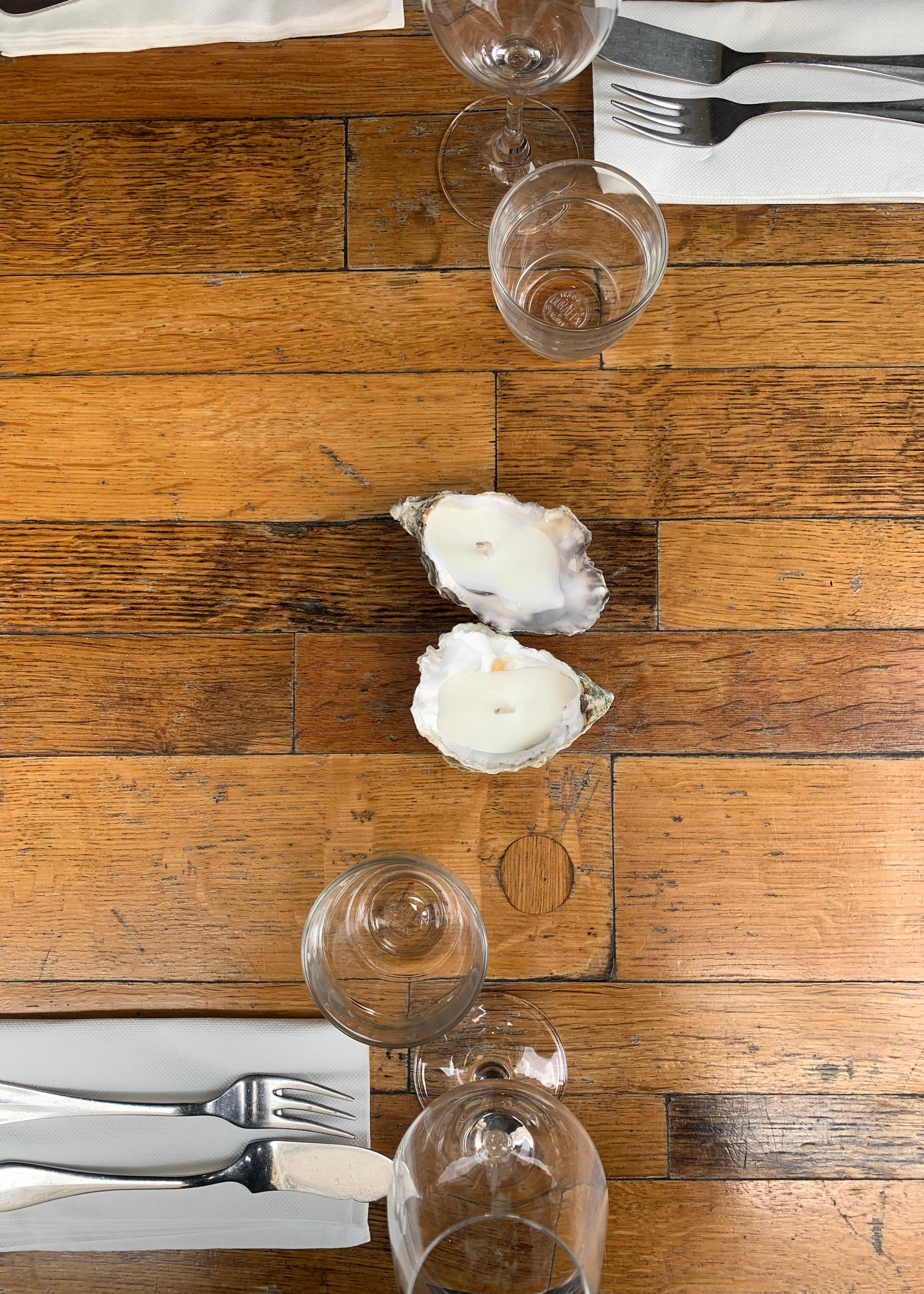 Oyster candles on a wooden table with wine glasses and cutlery