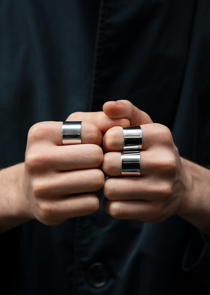 Close-up of hands wearing multiple silver rings on a dark background