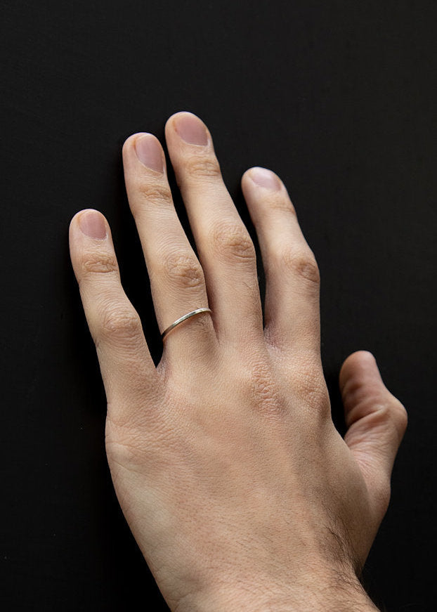Hand with a silver ring on a black background