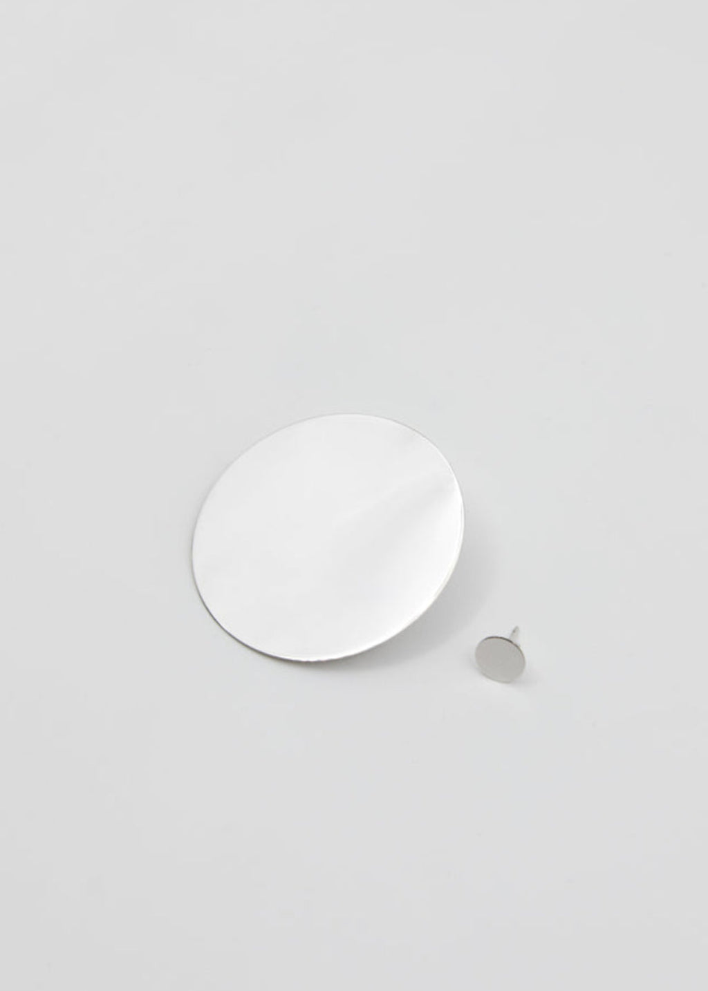 White circular earrings on a light gray background