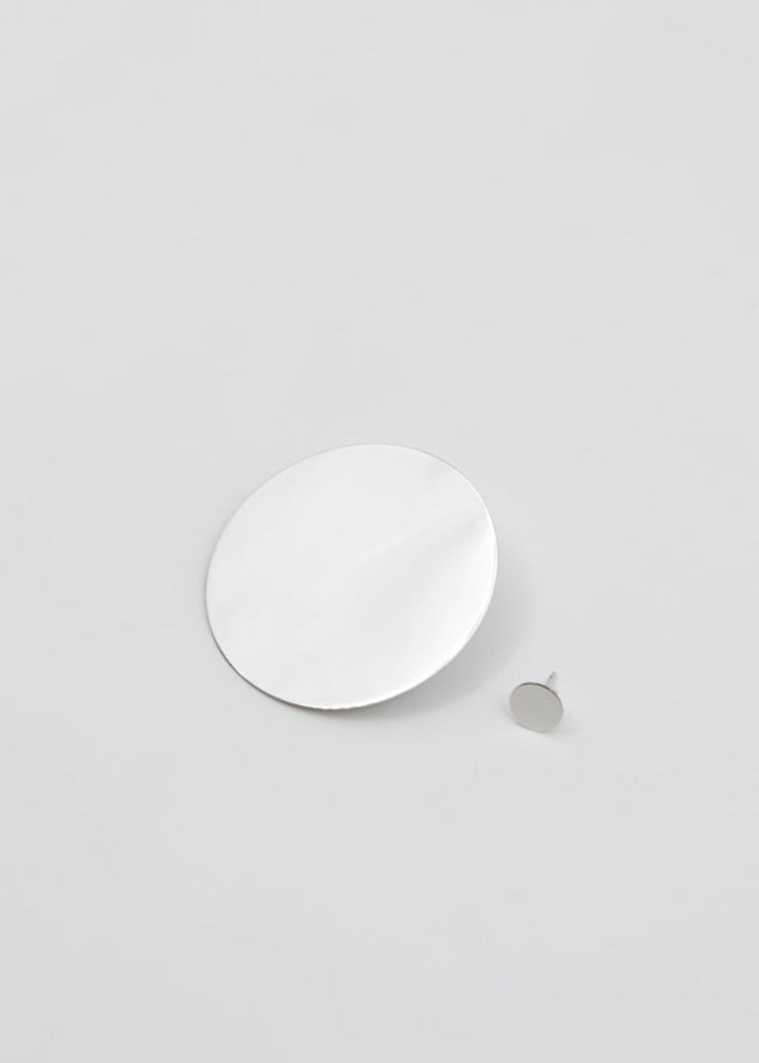 White circular earrings on a light gray background