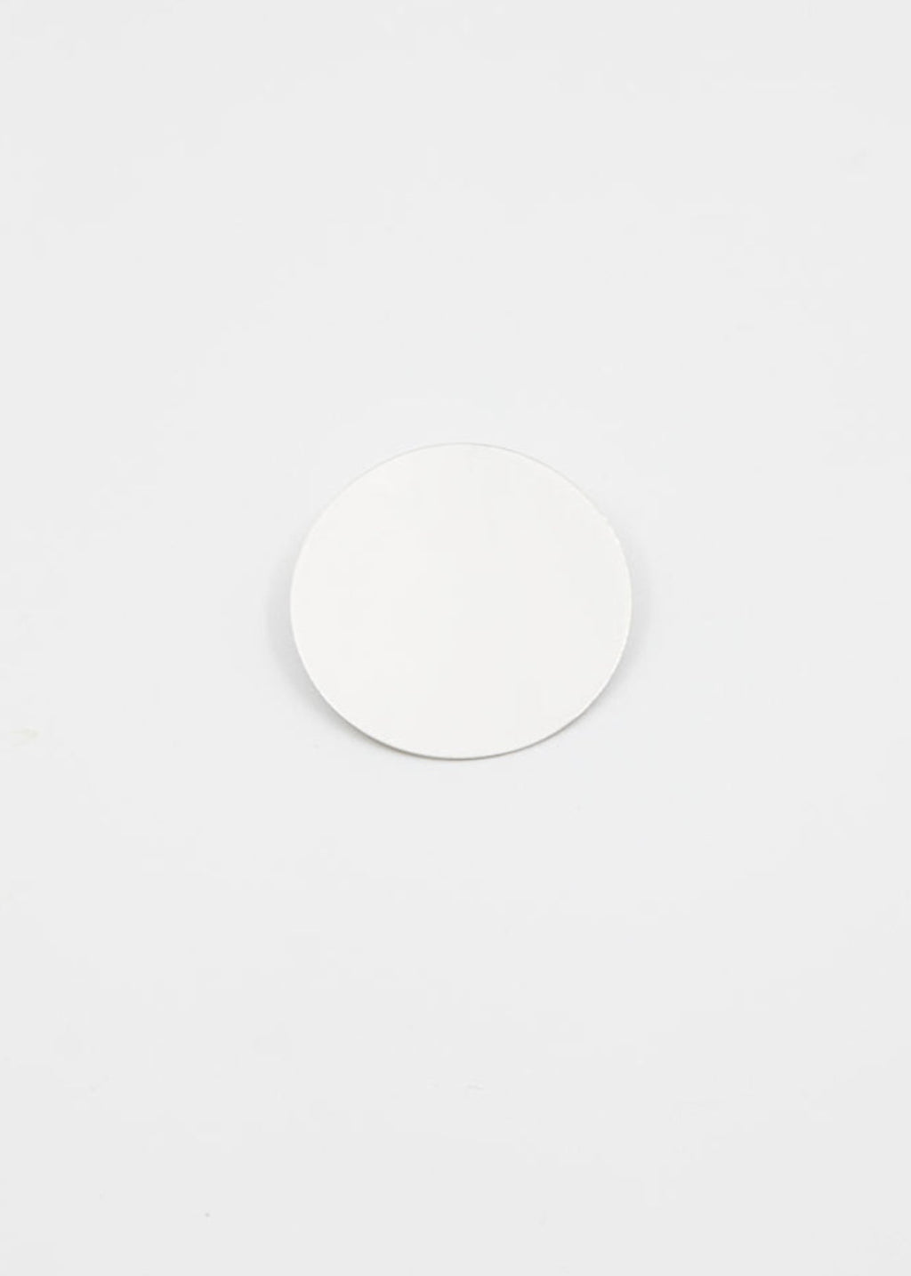 Large circular silver earring on a grey surface