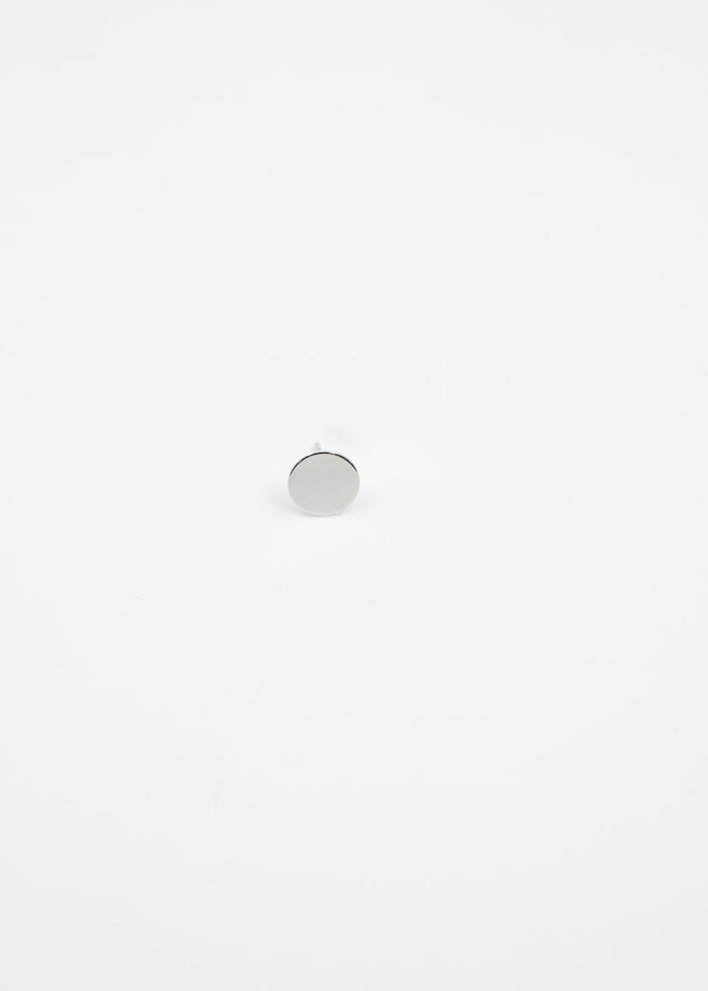 Small round silver ear stud on a white background