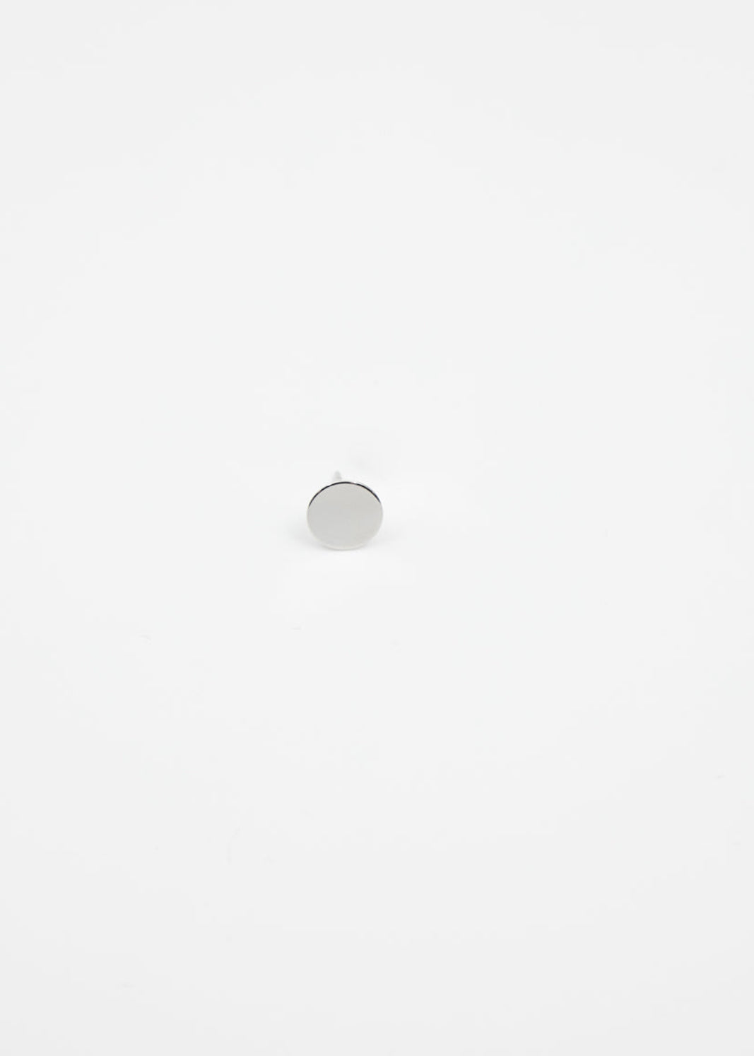 Small round silver ear stud on a white background