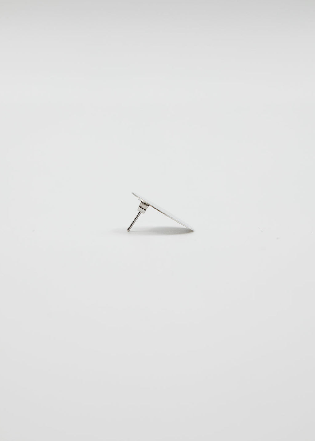 Silver earring on a light gray background