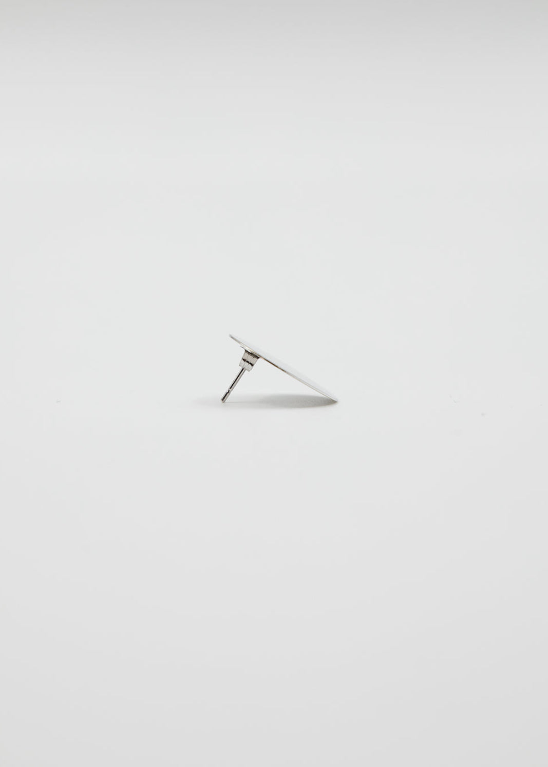 Silver earring on a light gray background