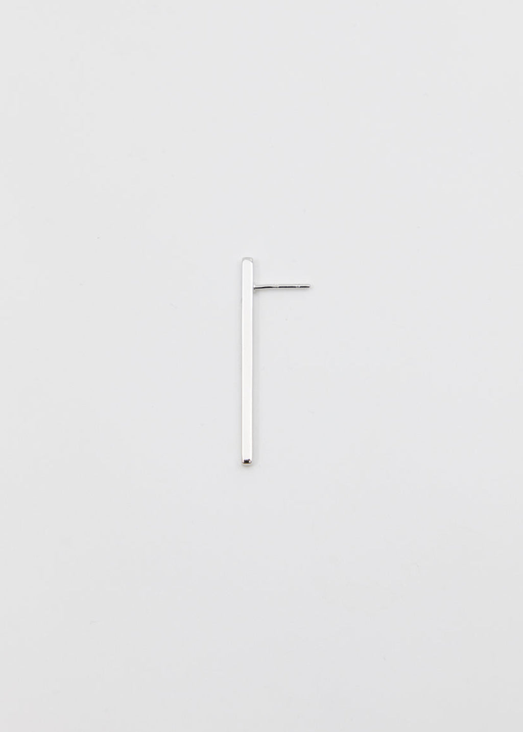 linear silver earring on a grey surface