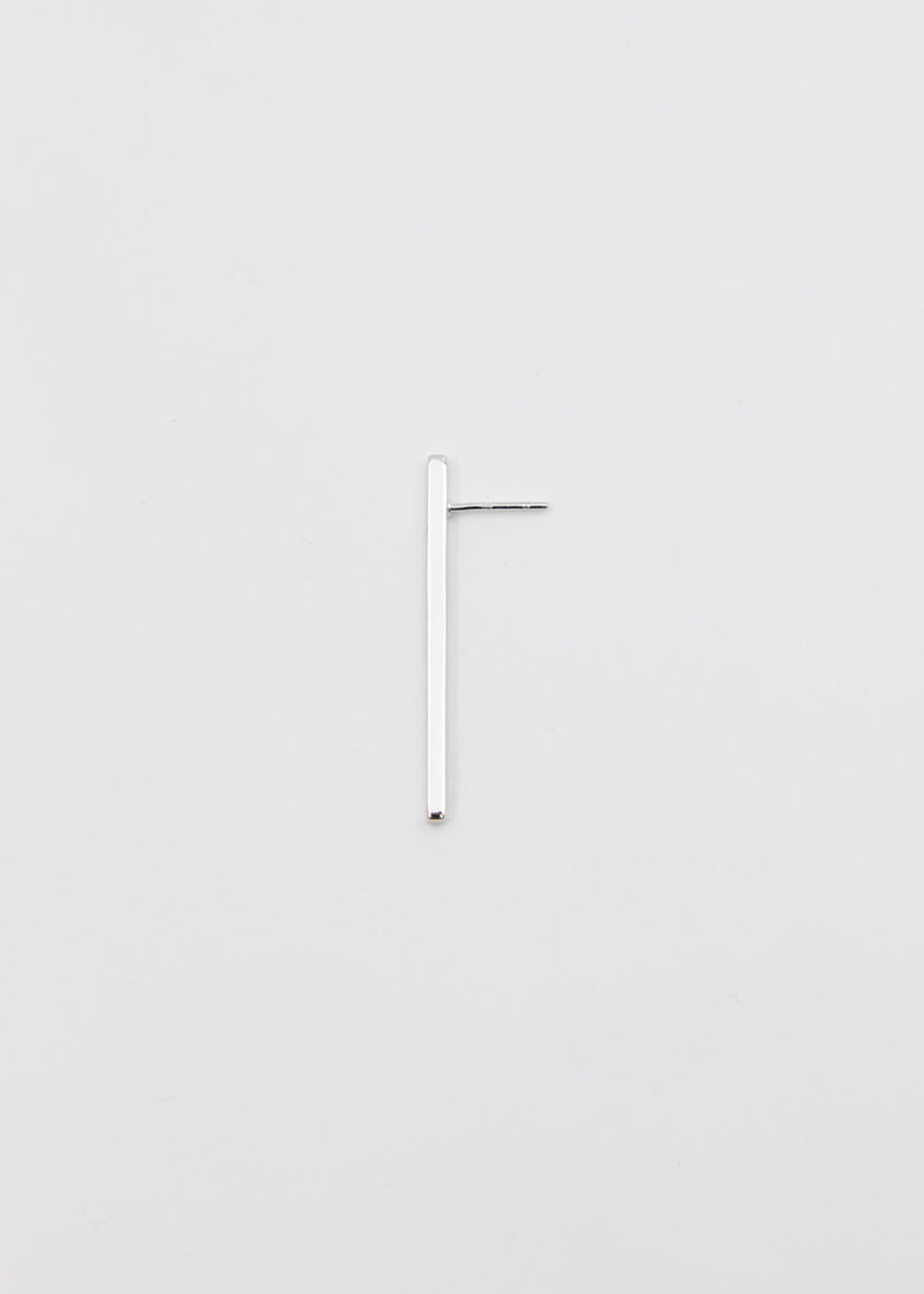linear silver earring on a grey surface