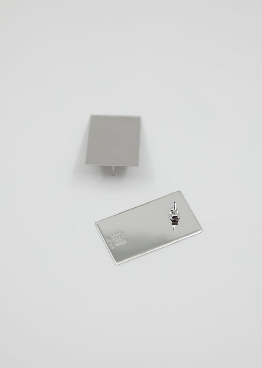 Two rectangular silver earrings on a white background