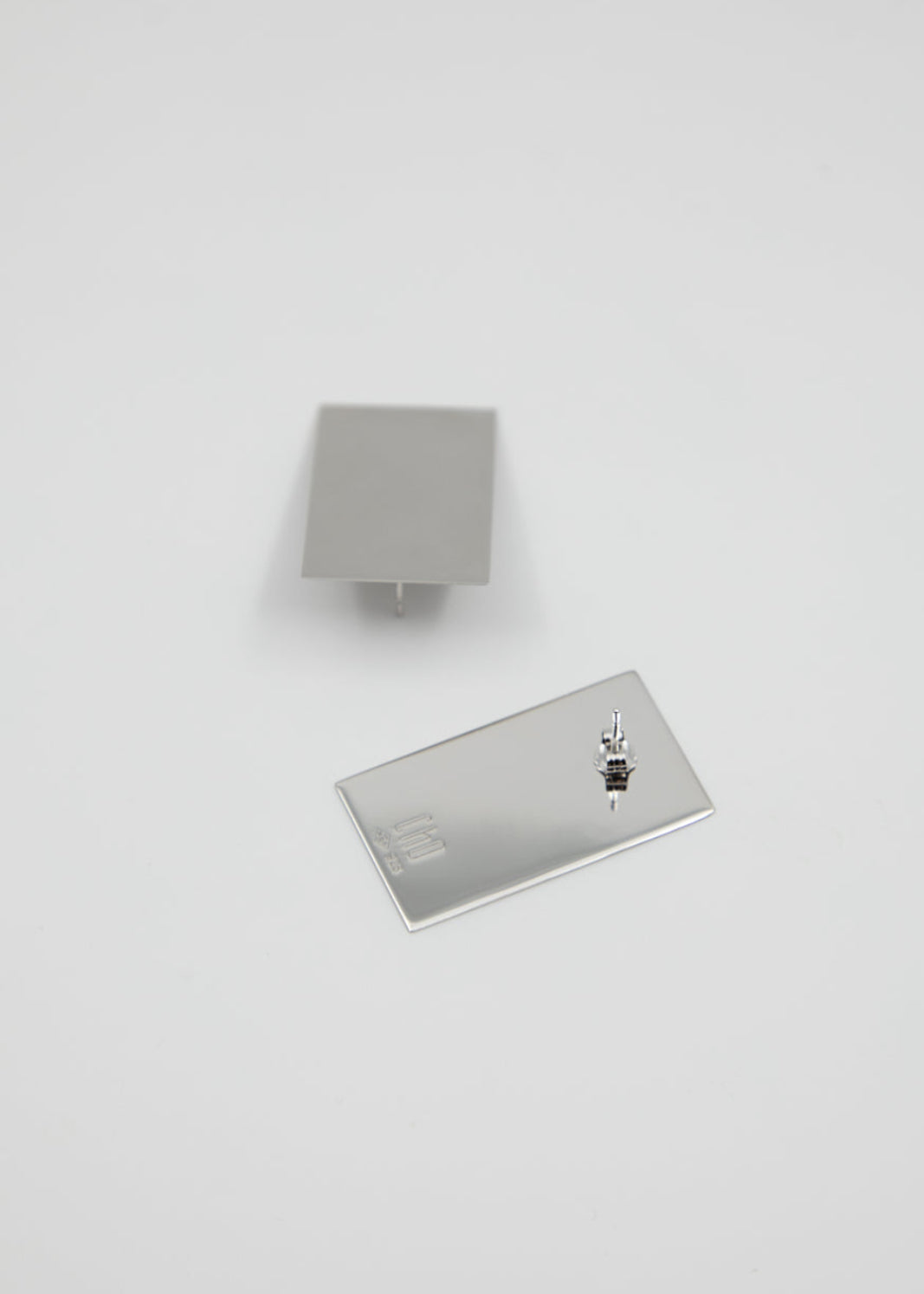 Two rectangular silver earrings on a white background