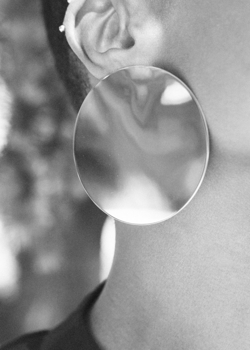 extra large mirror-reflective circular earring on a person
